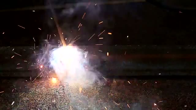 A welding torch joining metal in a production cell.