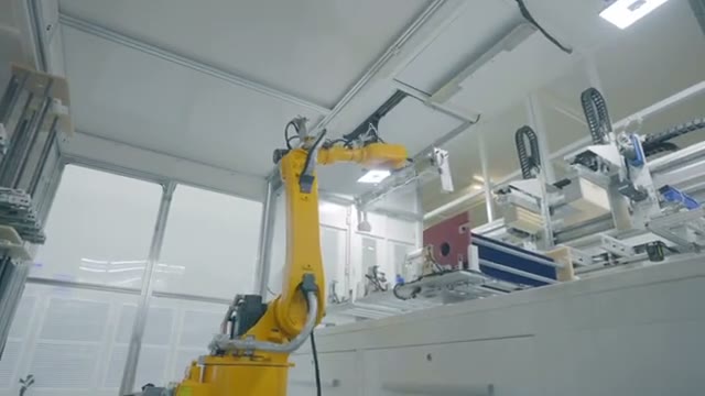 A yellow robot transferring material between machines.